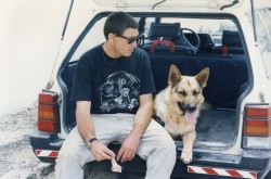 איש וכלב יושבים מאושרים בתא המטען של מכונית- אילוף כלבים, פנסיון כלבים