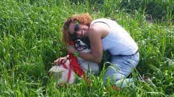 אישה וכלב מאושרים מתחבקים בשדה- אילוף כלבים, פנסיון כלבים